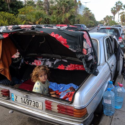 Ein verschlafener Junge sitzt im Kofferraum eines Autos im Libanon