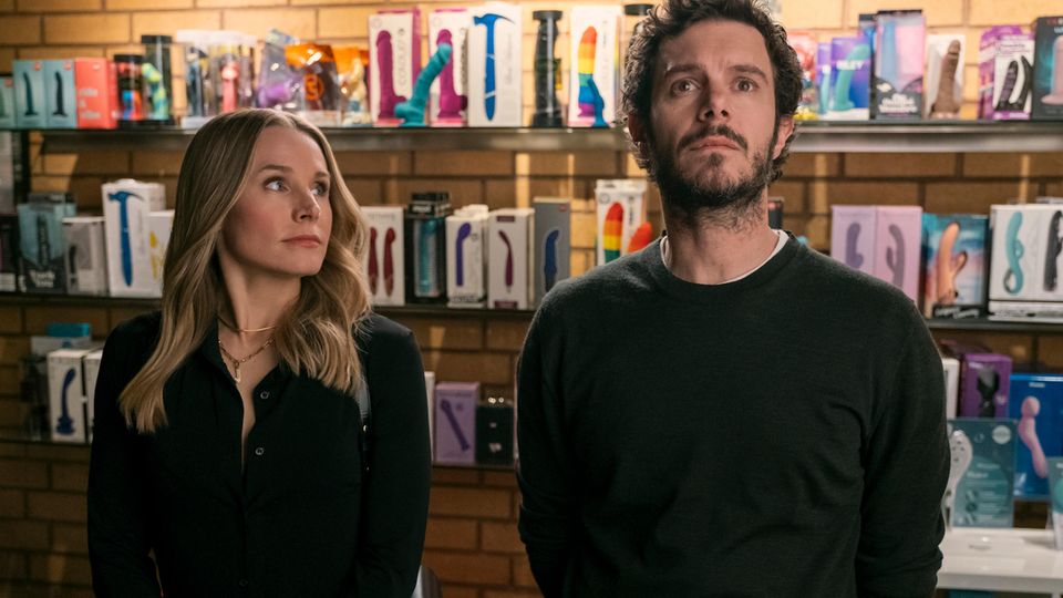 die Protagonisten stehen in einem Sexshop vor einem Regal mit Dildos