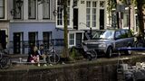 zwei junge Leute sitzen an einer Gracht in Amsterdam