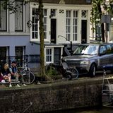 zwei junge Leute sitzen an einer Gracht in Amsterdam