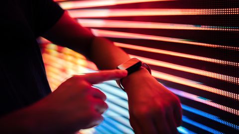 Eine Person hält eine Apple Watch an eine Jalousie