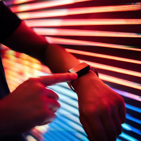 Eine Person hält eine Apple Watch an eine Jalousie