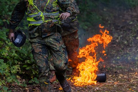 Zwei verletzte Soldaten der Bundeswehr rennen nach einem zu früh ausgebrochenen Feuer bei einer Katastrophenschutzübung