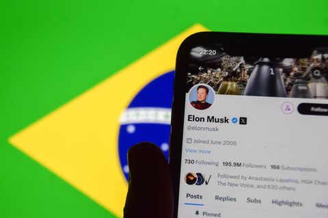Ein Handy mit dem Twitter-Profil von Elon Musk auf X, im Hintergrund die Flagge Brasiliens