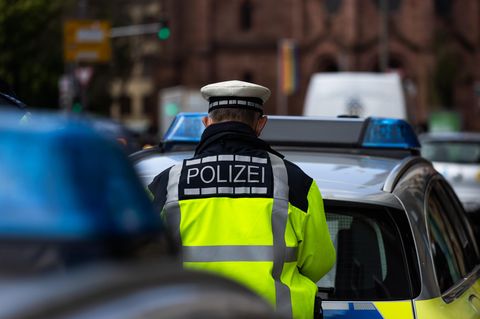Straftäter gefasst: Ein Polizeibeamter steht zwischen zwei Einsatzfahrzeugen.