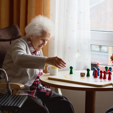 Eine Seniorin spielt einer Frau, ein Brett Spiel am Tisch