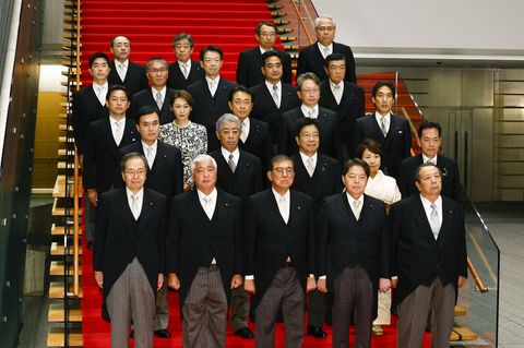 Eine Gruppe Männer und Frauen aus Japan posieren in Fracks und Kostümen auf einer Treppe für ein Gruppenfoto