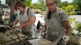Der erste Schritt ist es die beschädigten Bücher zu waschen so wie es hier zwei Mitarbeiterinnen mit einer art Duschkopf tun