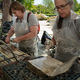 Der erste Schritt ist es die beschädigten Bücher zu waschen so wie es hier zwei Mitarbeiterinnen mit einer art Duschkopf tun