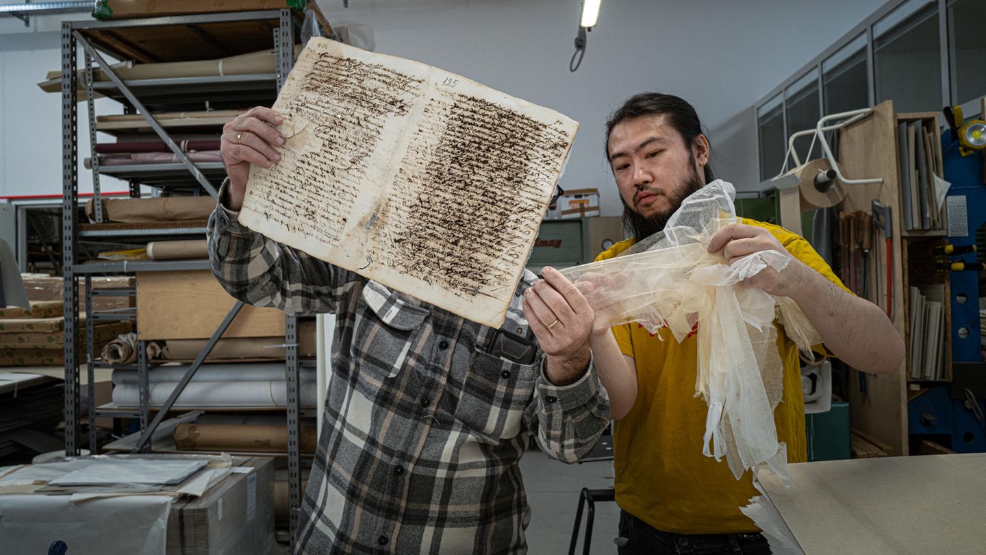 Japanpapier zur Restaurierung der beschädigten Buchseiten Ein Restaurator zeigt dem Eigentümer ein traditionelles Japanisches Papier, mit dem ein antikes Buch restauriert wurde.