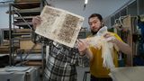 Ein Restaurator zeigt dem Eigentümer ein traditionelles Japanisches Papier, mit dem ein antikes Buch restauriert wurde.