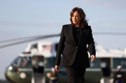 Kamala Harris geht auf den Betrachter zu auf dem Flugfeld. Im Hintergrund der Hubschrauber der Vizepräsidentin "Marine Two"