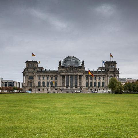 Ein Blick von weit weg auf den Bundestag mit dunklen Wolken im Hintergrund