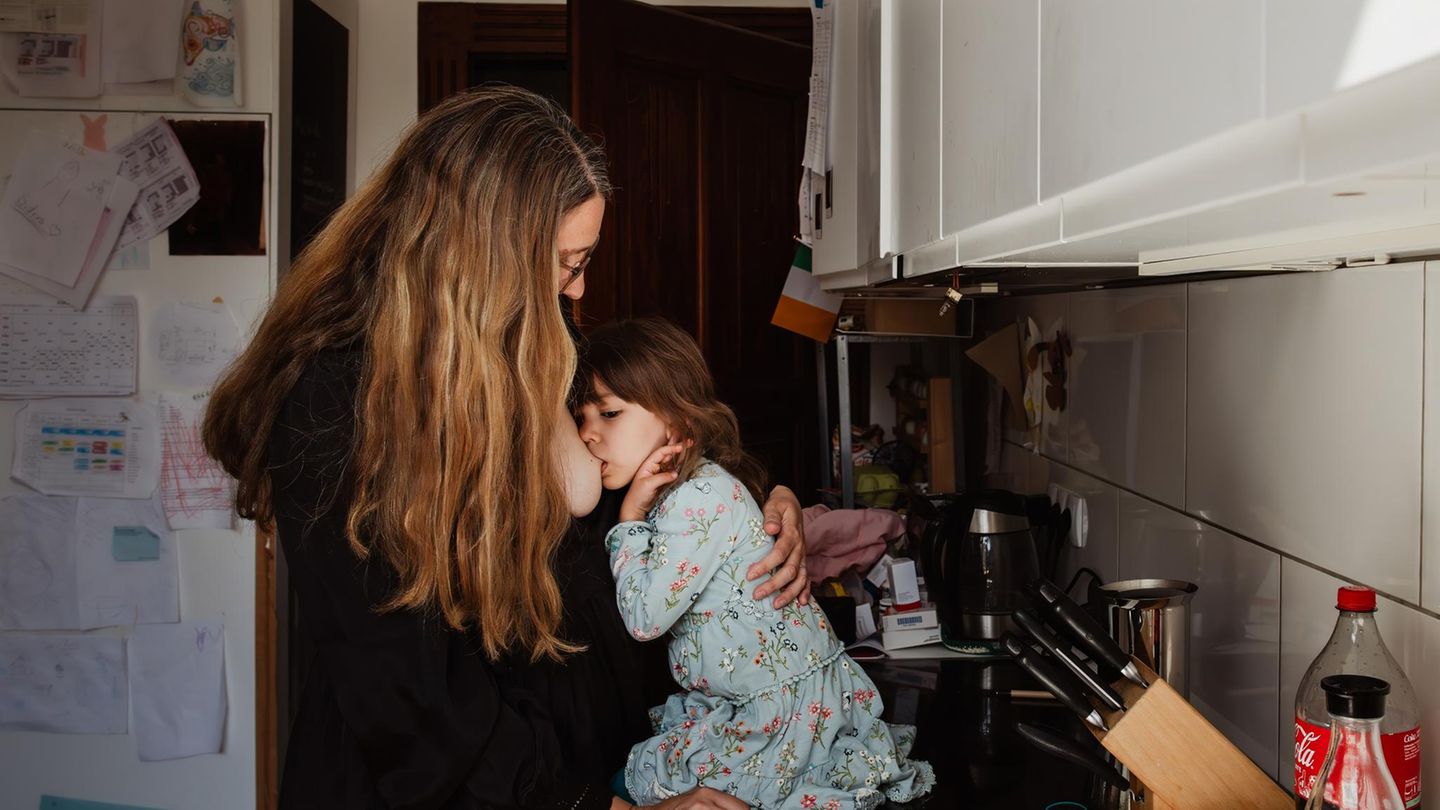 Eine Mutter steht mit ihrem Kind in der Küche und stillt