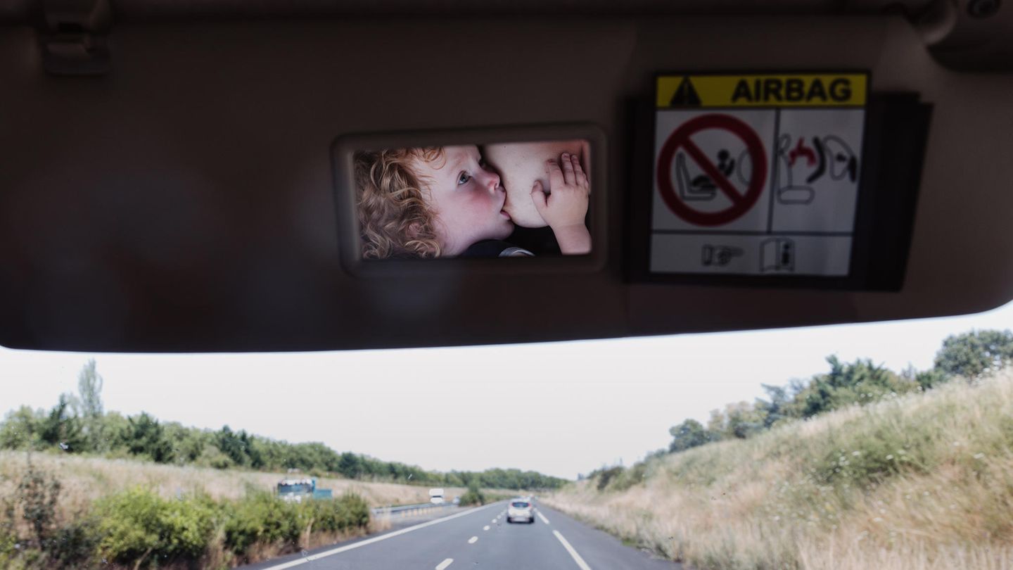 Im Rückspiegel eines Autos sieht man das Kind der Fotografin, das gerade gestillt wird