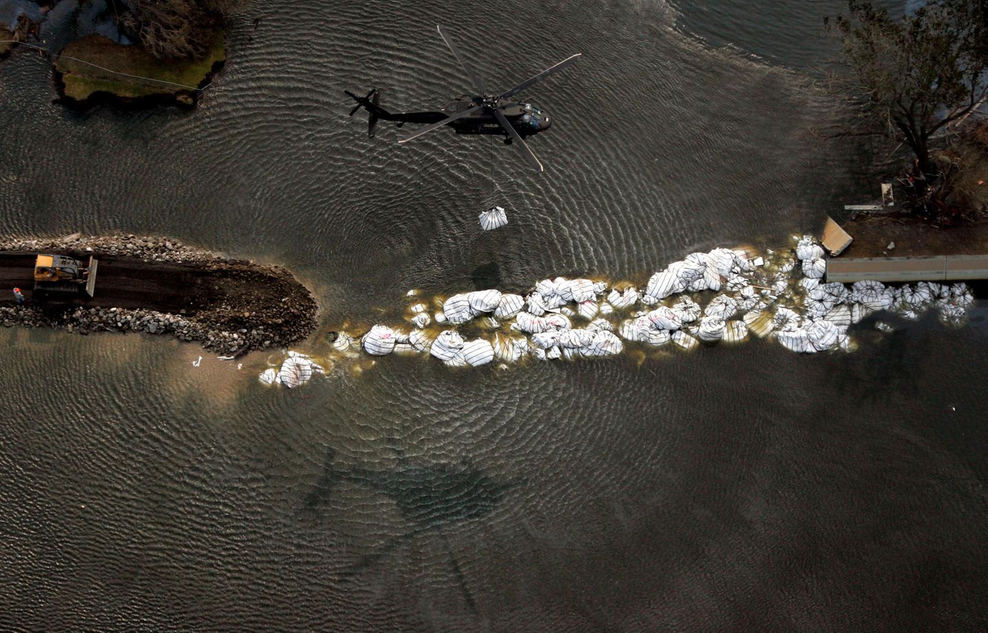 Ein Helikopter trägt Sandsäcke zu einem übergelaufenen Fluss Ein Helikopter trägt Sandsäcke zu einem übergelaufenen Fluss