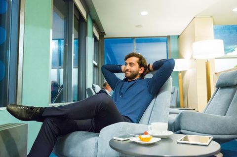 Amex Platinum Card: Mann sitzt entspannt in einem Sessel in einer Flughafen-Lounge