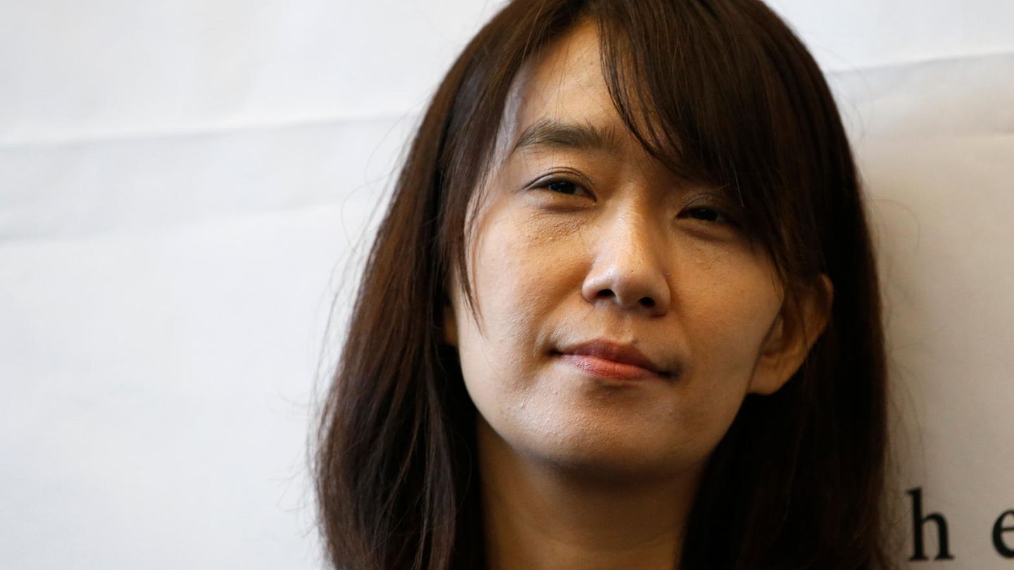 Die südkoreanische Schriftstellerin Han Kang steht mit nach links geneigtem Kopf vor einer weißen Wand