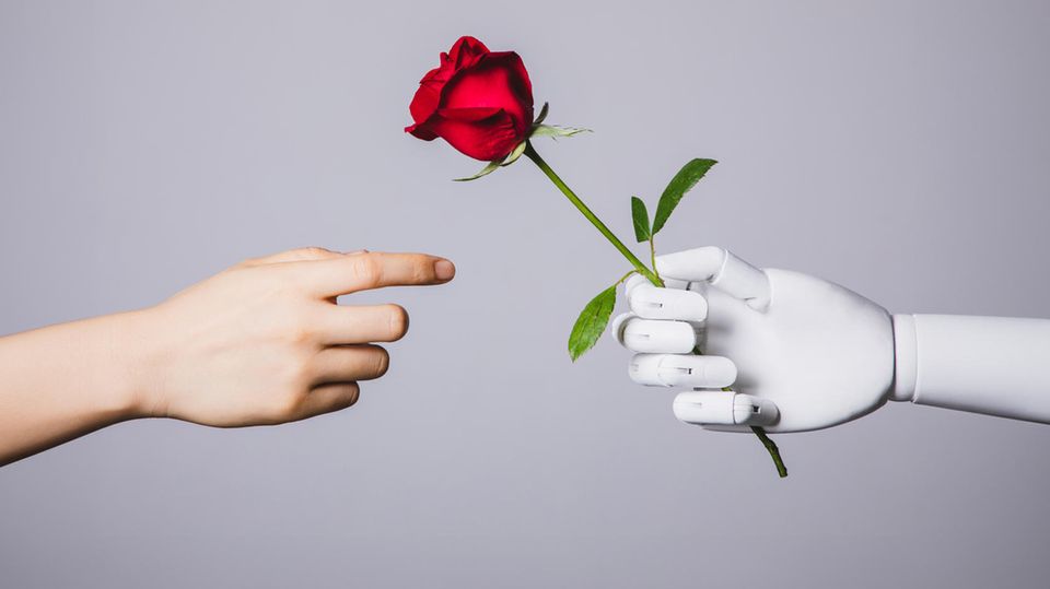 Eine menschliche Hand nimmt eine Rose von einer Roboterhand entgegen