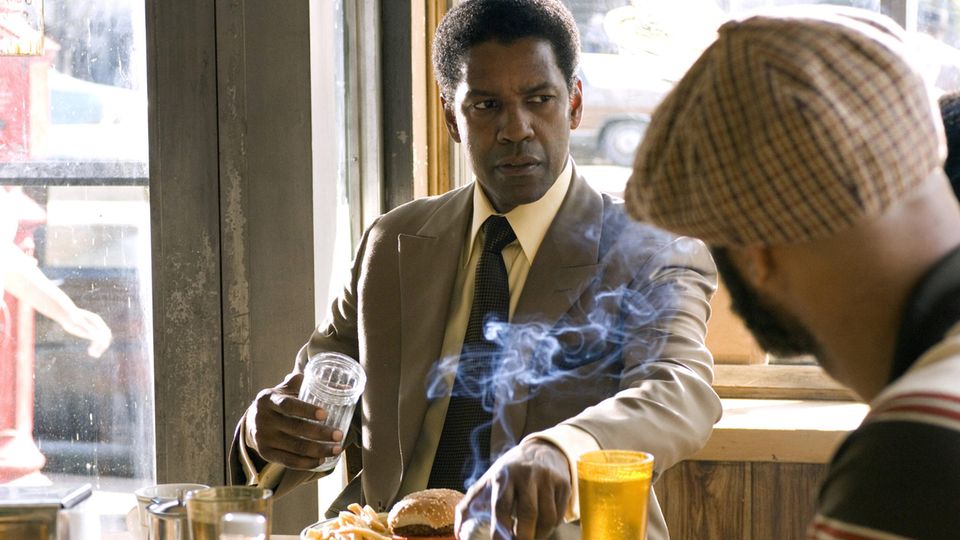 Denzel Washington sitzt am Tisch vor ihm ein Teller mit einem Burger