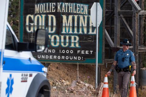 Ein Polizist verschiebt an der Mollie Kathleen Goldmine eine Absperrung für ein Einsatzfahrzeug