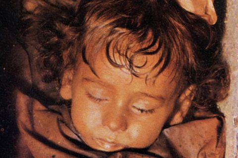 Gesicht der Mumie der kleinen Rosalia im offen Sarg mit gelber Haarschleife