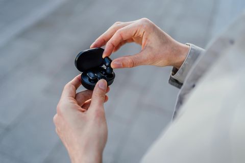 Person hält In-Ear-Kopfhörer in der Hand