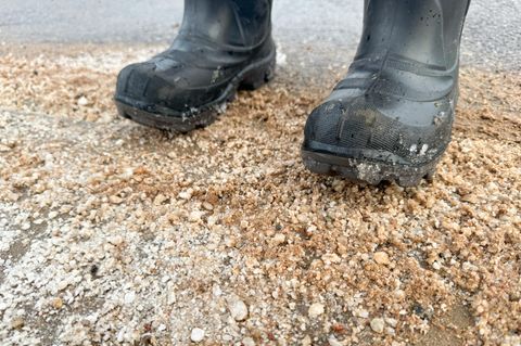 Mit Gummistiefeln auf einer Sandstraße mit Salz stehen