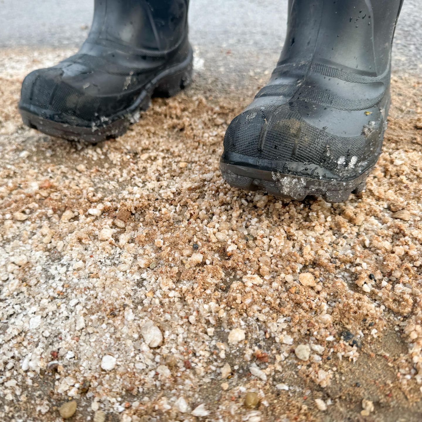 Mit Gummistiefeln auf einer Sandstraße mit Salz stehen