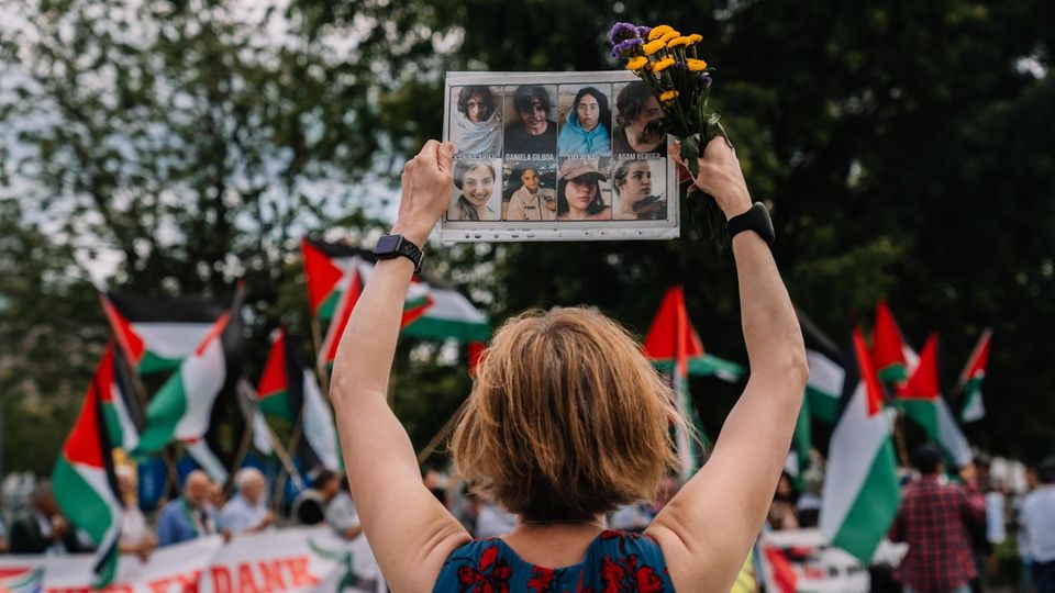 Karoline Preisler hält ein Schild mit Gesichtern bei einer Pro-Palästina Demo hoch