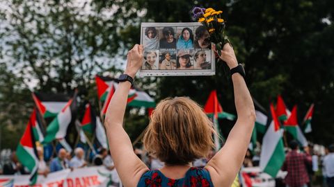 Karoline Preisler hält ein Schild mit Gesichtern bei einer Pro-Palästina Demo hoch