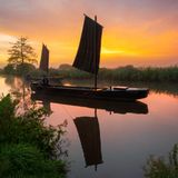 Drei Kähne fahren bei Sonnenaufgang durch einen Kanal im Teufelsmoor