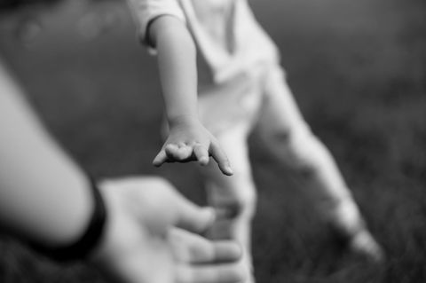 Eine Kinderhand greift nach der Hand des Vaters