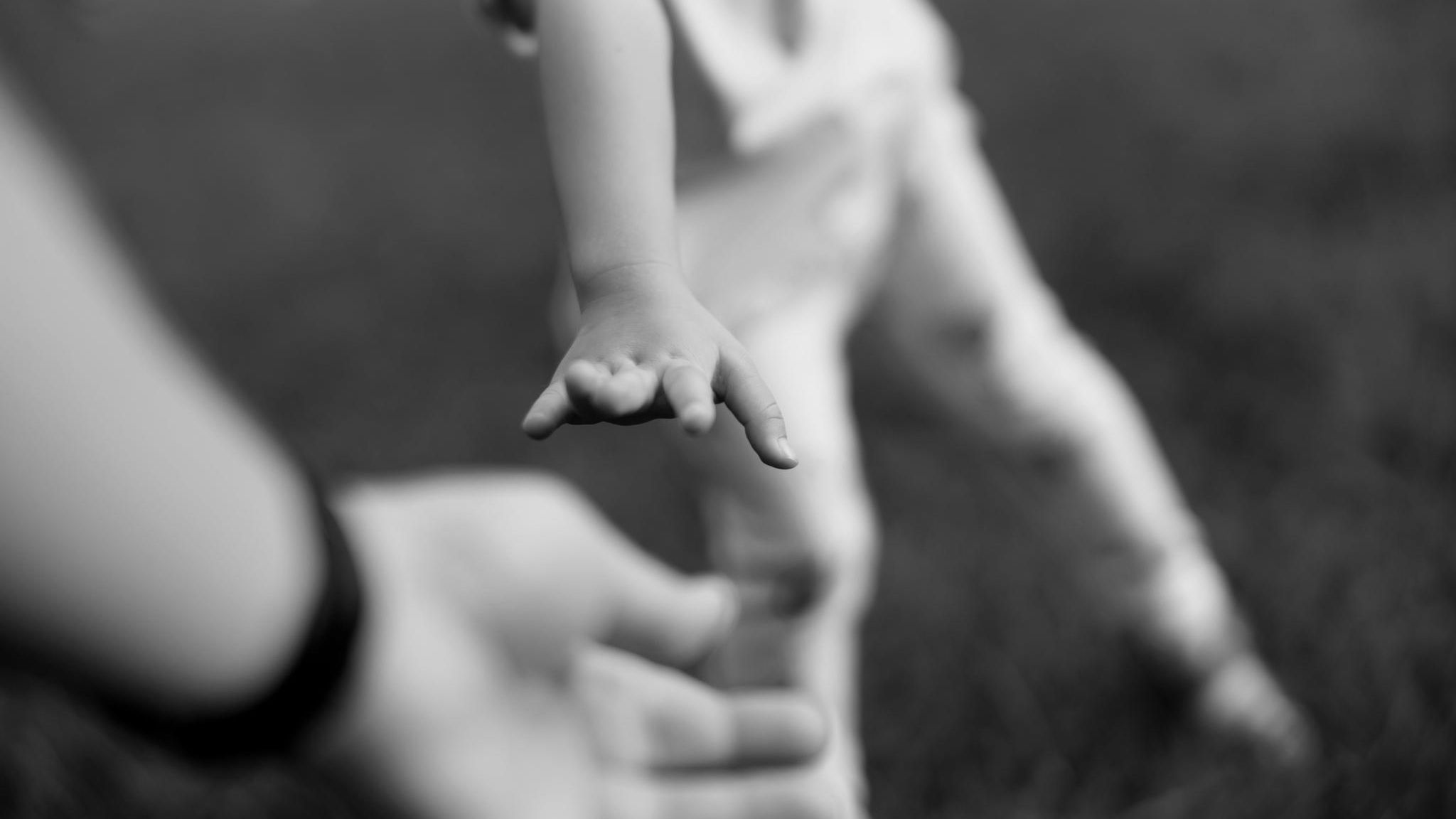 Eine Kinderhand greift nach der Hand des Vaters
