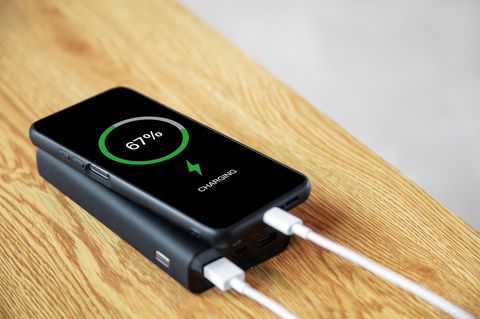 Ein Mann lädt sein Handy mit einer Powerbank.