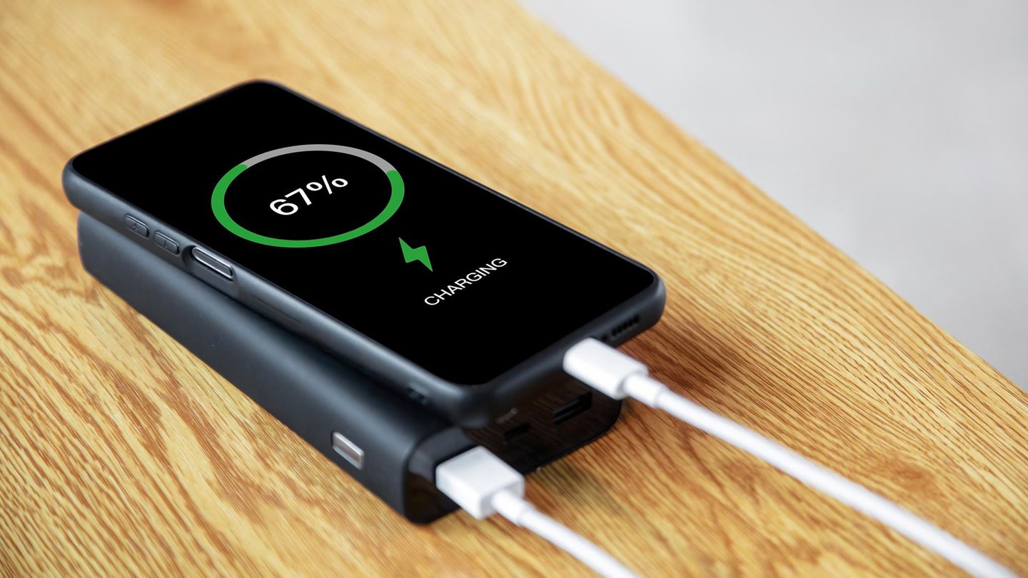 Ein Mann lädt sein Handy mit einer Powerbank.