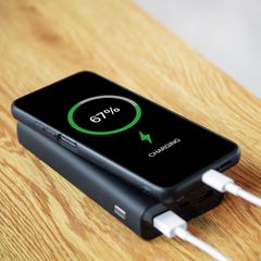 Ein Mann lädt sein Handy mit einer Powerbank.