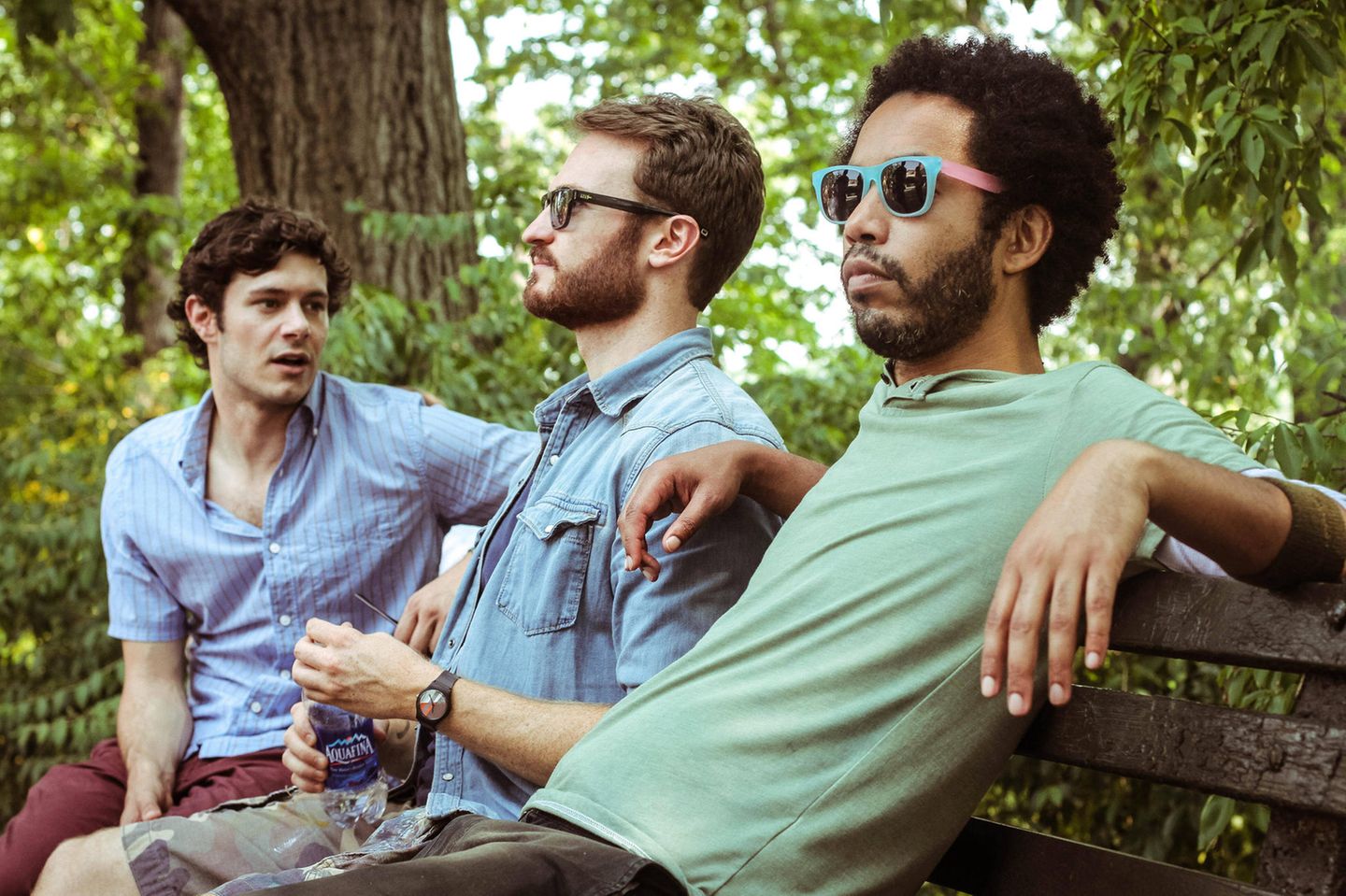 Adam Brody sitzt mit zwei Kollegen auf einer Bank – in einer Filmszene