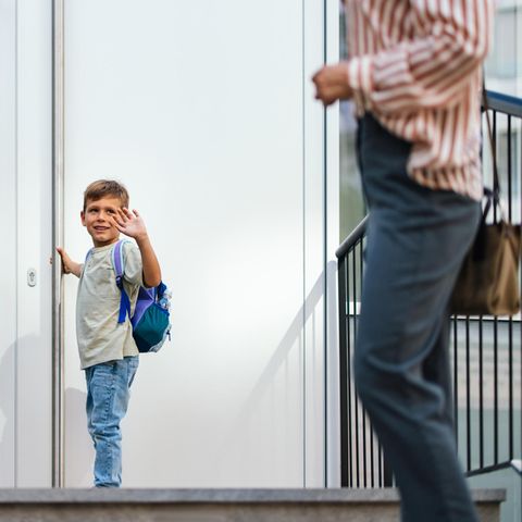Trennung mit Kindern: Ein kleiner Junge winkt seiner Mutter zu, bevor er die Tür zu seinem Zuhause öffnet