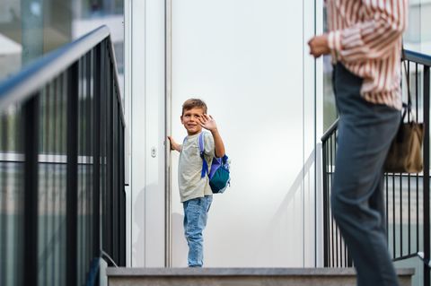Trennung mit Kindern: Ein kleiner Junge winkt seiner Mutter zu, bevor er die Tür zu seinem Zuhause öffnet