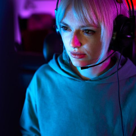 Eine junge Frau sitzt vor einem Bildschirm mit Kopfhörern und spielt League