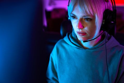 Eine junge Frau sitzt vor einem Bildschirm mit Kopfhörern und spielt League