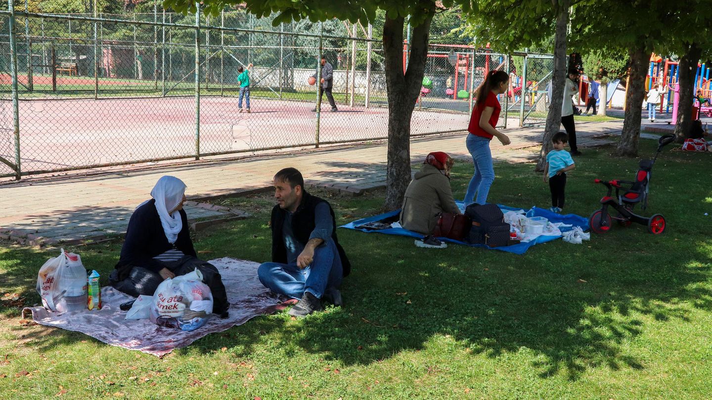 Nach einem Erdbeben in der Türkei sitzen Menschen auf Decken in einem Park