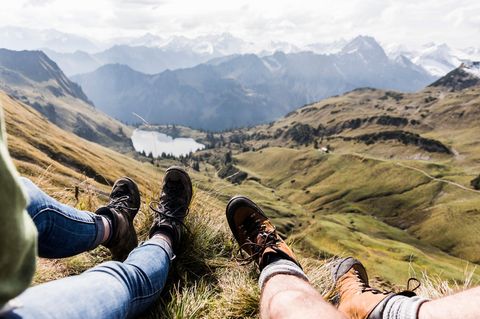 Zwei Personen liegen auf einer Wiese in den Bergen