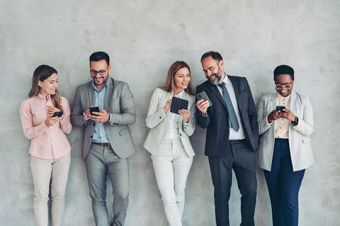 Datenvolumen einschätzen: Eine Gruppe von Menschen in Business-Kleidung bei der Smartphone-Nutzung.