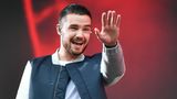 Sänger Liam Payne mit In Ear Kopfhörern und winkt.