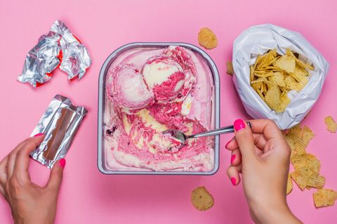 Ein Pinker Tisch mit vielen ungesunden Lebensmitteln darauf – lädt zum Stressessen ein