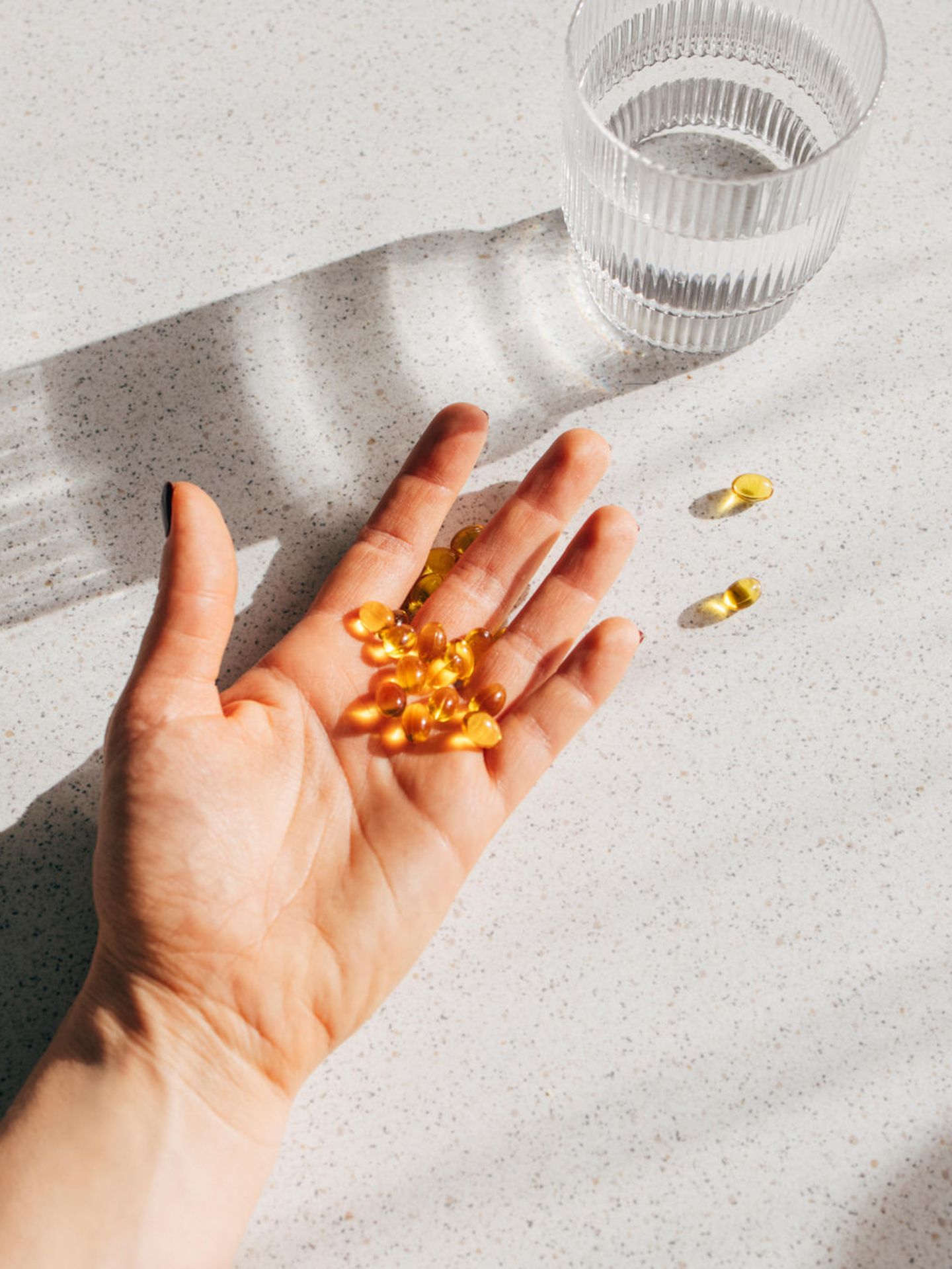 Eine Hand voller Vitamin D Tabletten liegt auf dem Tisch