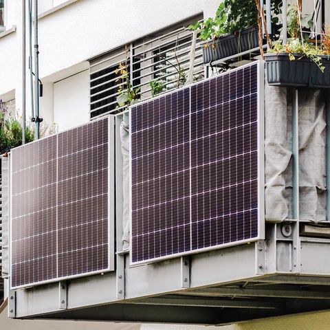Balkonkraftwerk-Speicher kaufen: Zwei Solarmodule am Balkongeländer eines Mehrfamilienhauses.