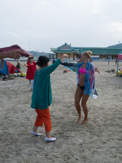 Nordkoreanerinnen laden die Touristinnen aus Russland zum Tanz. Die Reisegruppe ist entweder gemeinsam am Strand - oder im Hotel. Die Zelte sollen vor der Sonne schützen, koreanische Sommer sind heiß und schwül